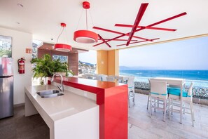 A modern kitchen with a red accent wall, a stainless steel sink, and a view of the ocean. - Perfect One Bedroom one block from the Beach! (Puerto Vallarta)