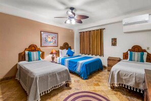 A hotel room with two beds, a ceiling fan, an air conditioner, a window with curtains, and a rug. - Tranquil Two Bedroom Condo in Zona Romantica (Puerto Vallarta)