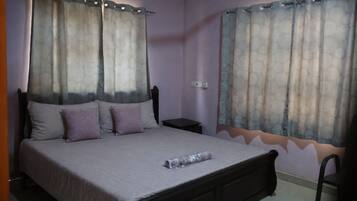 A bedroom with a bed, pillows, a nightstand, and curtains.
