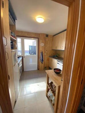 A kitchen with wooden cabinets, a sink, a stove, and a window. - Holiday Home 'Casa Vistas Almijara Nerja' with Sea View, Wi-Fi and Air Conditioning (Nerja)