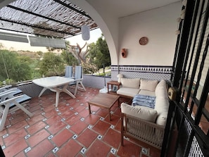 An outdoor patio with a table and chairs, a sofa, and a decorative wall. - Holiday Home 'Casa Vistas Almijara Nerja' with Sea View, Wi-Fi and Air Conditioning (Nerja)