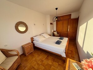 A bedroom with a bed, a chair, a wardrobe, a mirror, and a hanging light fixture. - Holiday Home 'Casa Vistas Almijara Nerja' with Sea View, Wi-Fi and Air Conditioning (Nerja)