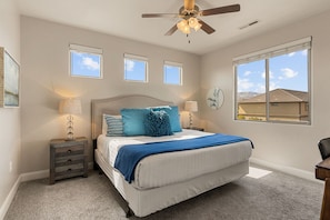 A bedroom with a bed, nightstands, a ceiling fan, and a large window. - Grand Resort #98: Private Pool + Sports Court (Santa Clara)