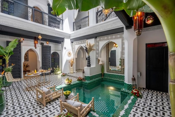A courtyard with a swimming pool, seating area, and decorative elements. - dar bonita (Marrakesh)