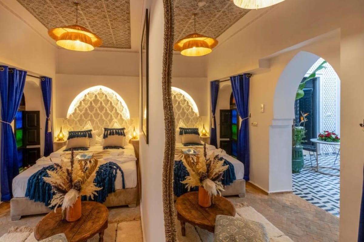 A mirrored room with a bed, two side tables, and a mirror.