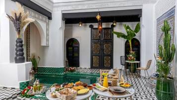 A courtyard with a dining setup, a fountain, and a decorative door.
