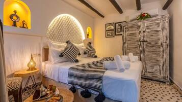 A cozy bedroom with a bed, a round lamp, a small table with snacks, and a decorative wall piece.
