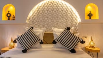 A bed with a geometric patterned headboard, two bedside lamps, and striped pillows.