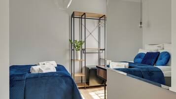 A modern hotel room with two beds, a mirror, a wardrobe, and a small plant.