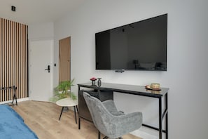 A modern bedroom with a bed, a desk with a chair, a television, and a wardrobe. - Lawendowa Old Town Signature Rooms with Shared Kitchen by Downtown Apartments (Gdańsk)