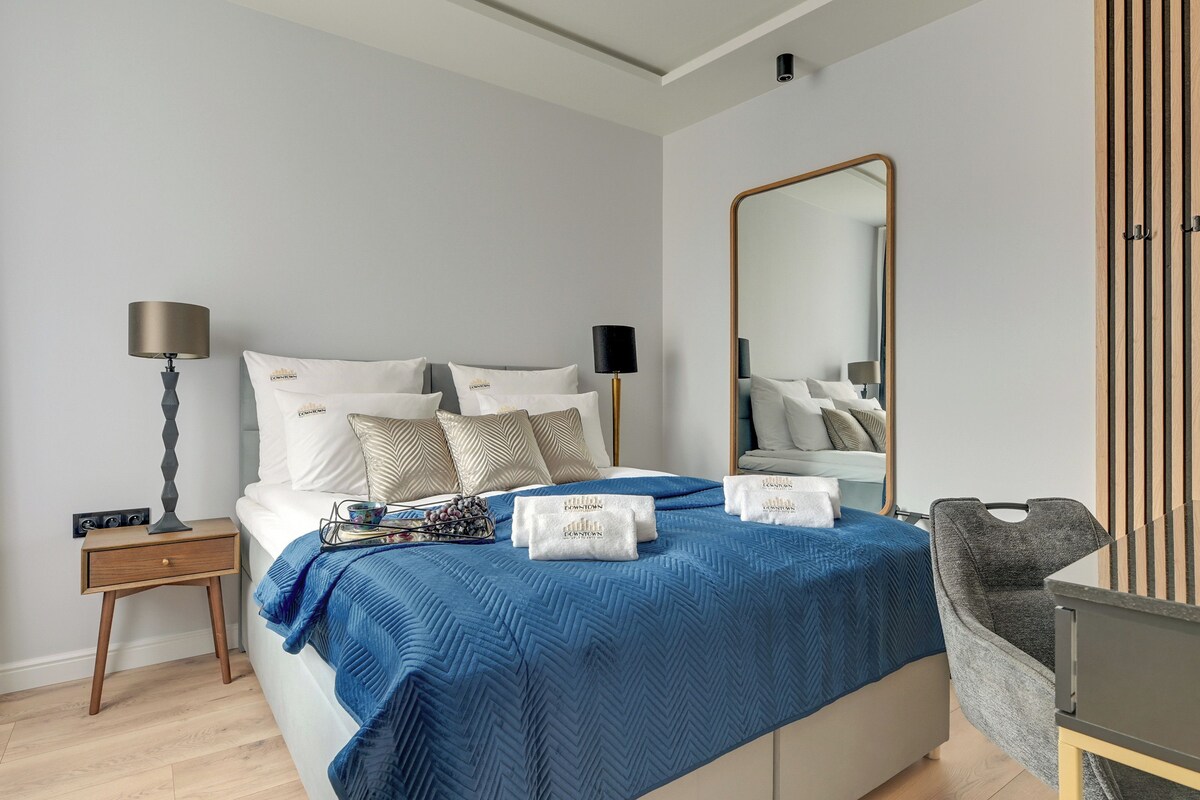 A modern bedroom with a bed, bedside tables, a mirror, and a chair.