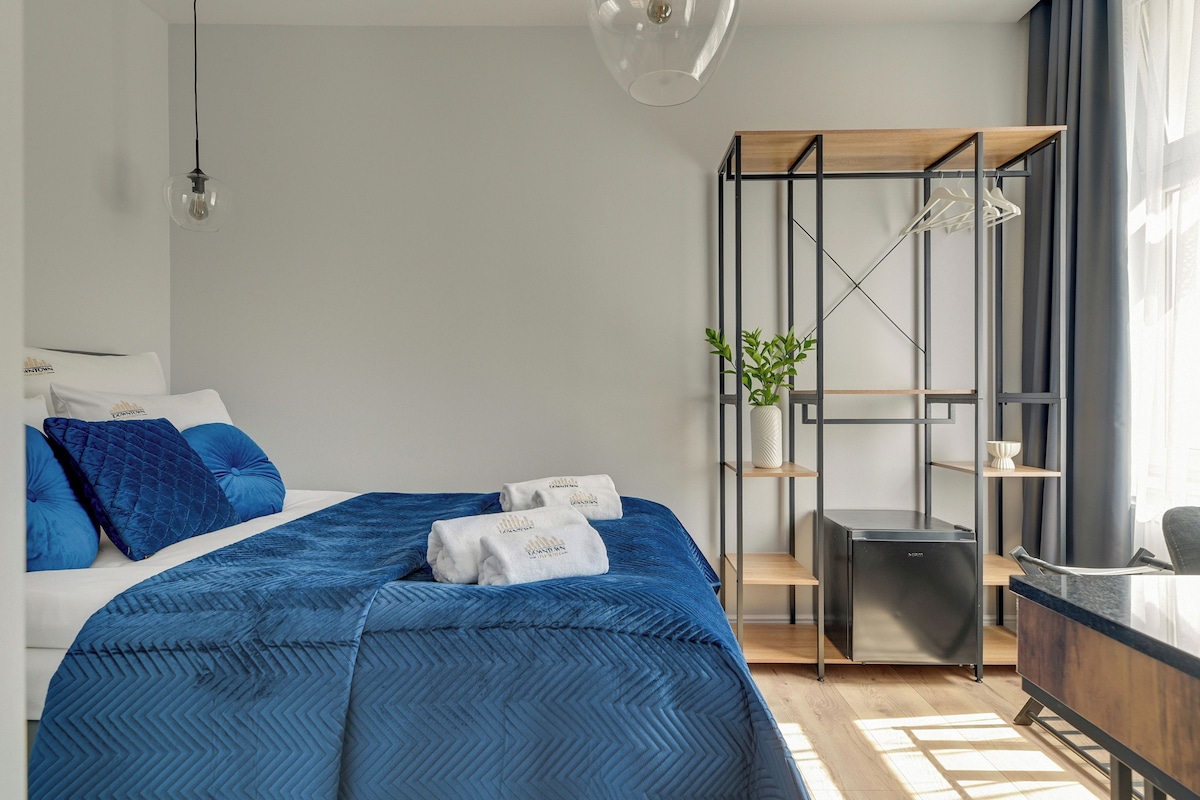 A modern bedroom with a bed, a desk, and a shelving unit.