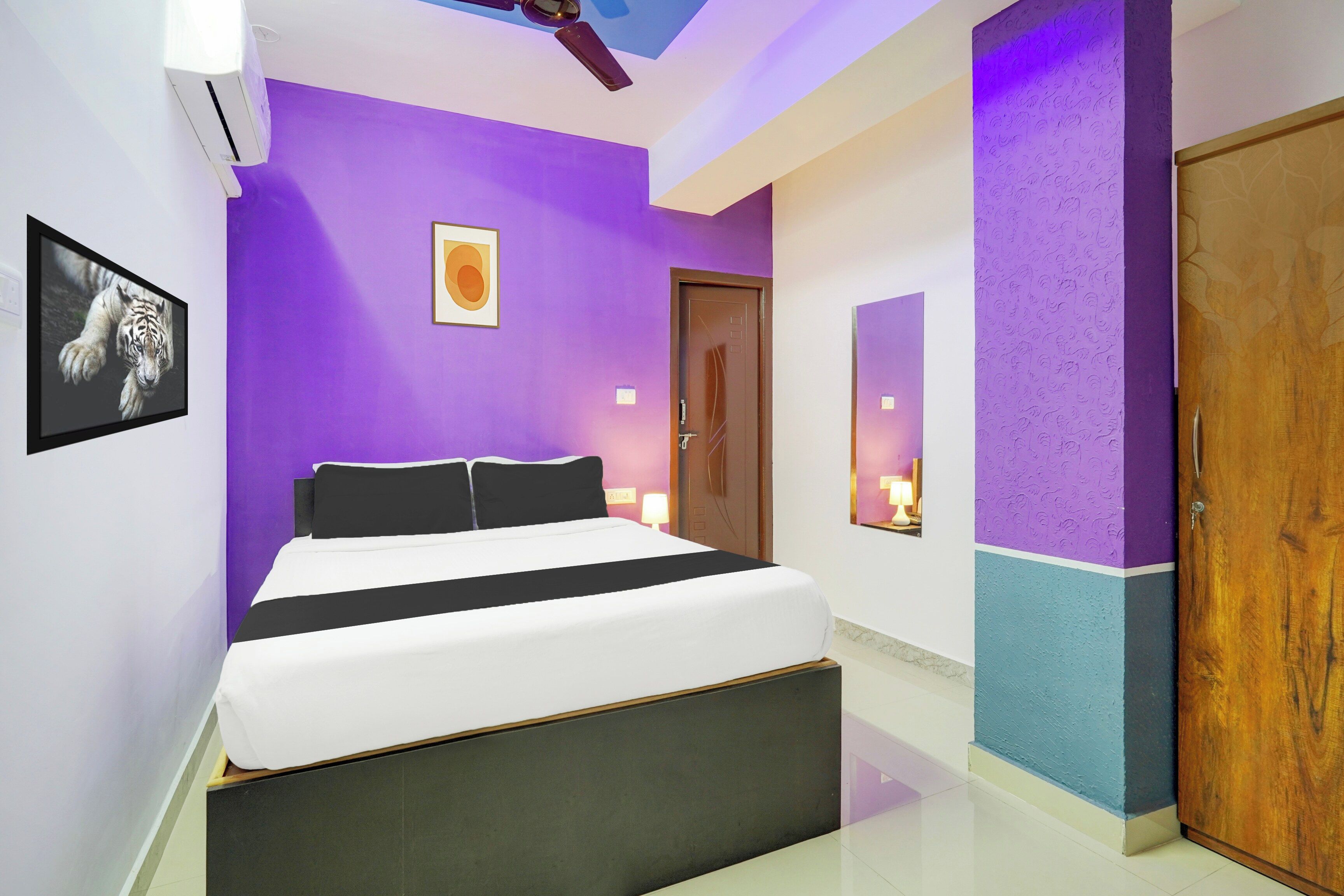 A modern bedroom with a bed, a wall-mounted air conditioner, and a door.