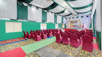 A hall with rows of chairs, a stage with a backdrop, and a patterned carpet.