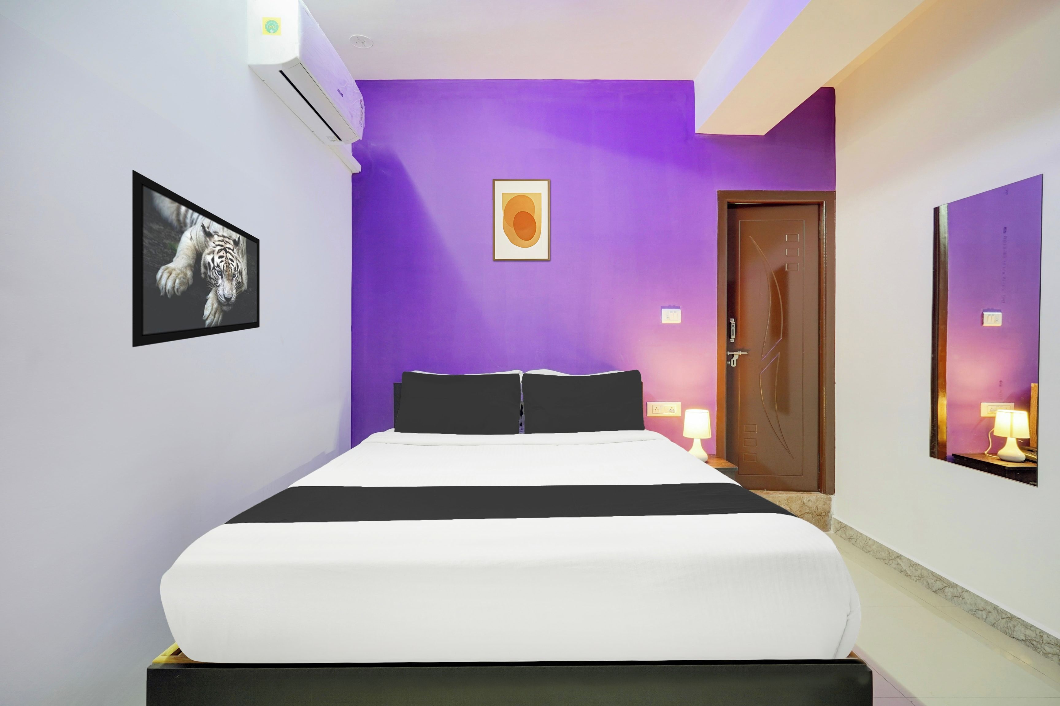 A bedroom with a bed, a door, and a wall-mounted air conditioner.