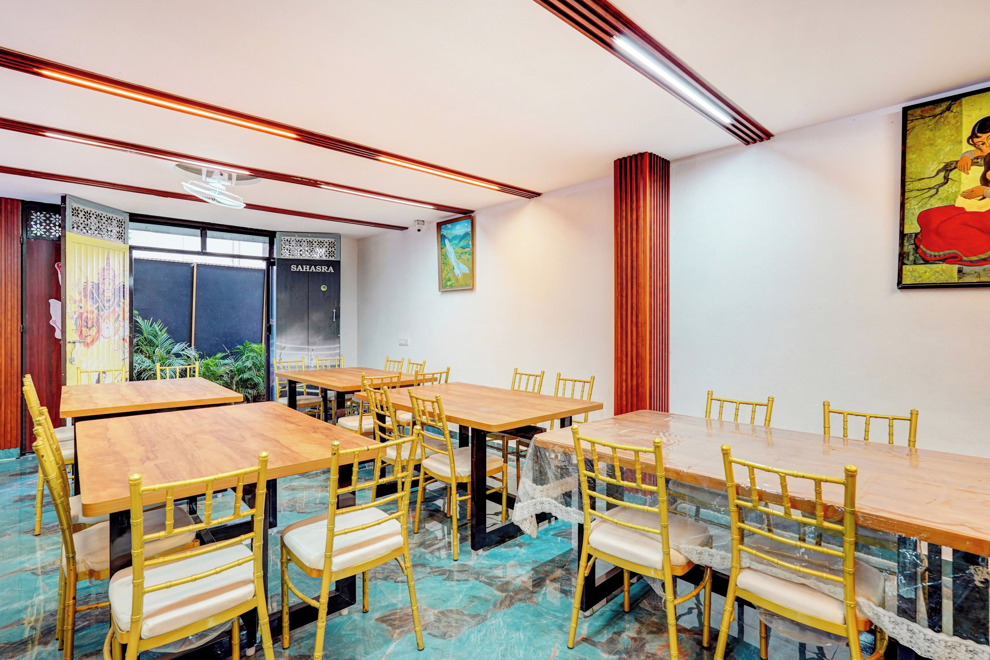 A conference room with multiple tables and chairs, a large window with a view, and a painting on the wall.