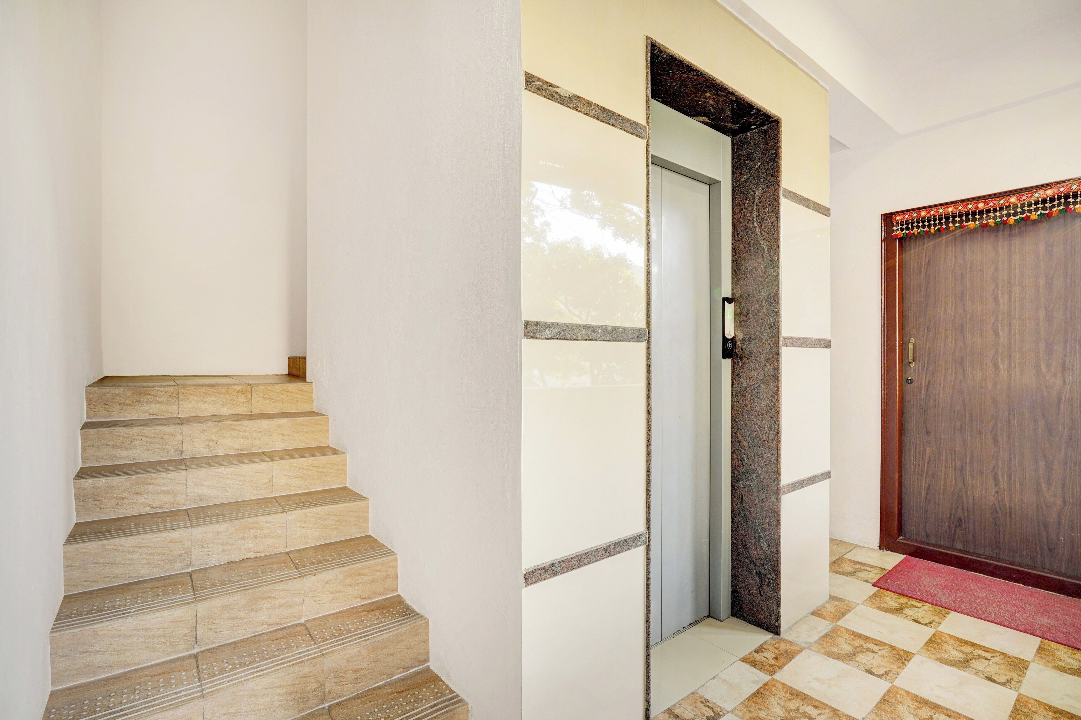 A staircase leading to a door with a textured wall and a red mat at the bottom.