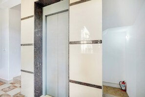 Un pasillo con puerta, paredes de baldosas y extintor.