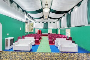 Una sala con filas de sillas, alfombra verde y un candelabro.