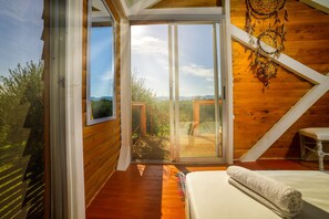 Ein Zimmer mit einem Bett, einem Fenster und Blick ins Freie.