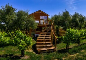 Eine Holzhütte mit einer Wendeltreppe, die zu einer Terrasse führt, umgeben von einem Weinberg.