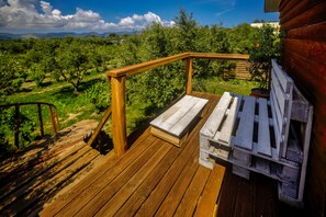 Eine Holzterrasse mit einer Bank und einem Tisch, mit Blick auf einen Weinberg.