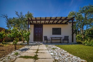 Un patio cubierto con una mesa, sillas, una puerta y una ventana.