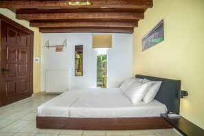 Ein Schlafzimmer mit einem hölzernen Bettgestell, einer weißen Matratze, einem Nachttisch, einem an der Wand befestigten Spiegel, einem Heizkörper und einer Tür.