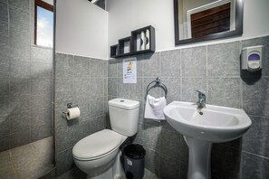 Un baño con inodoro, lavamanos y un cubo de basura.