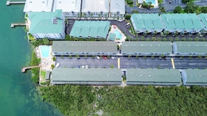An aerial view of a hotel with multiple buildings, a parking lot, and a swimming pool. - Fishing Pier | Heated Community Pool | Quick Walk to the Beach | Sea Shell #32 (Indian Shores)
