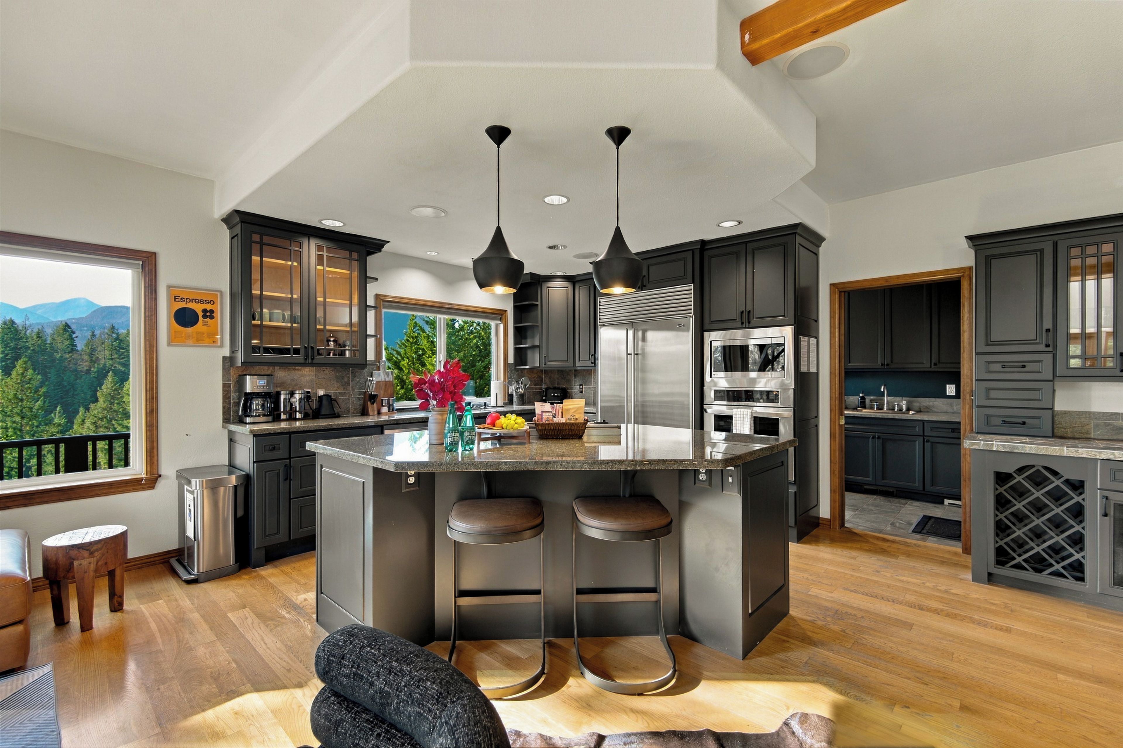 A modern kitchen with a large island, stainless steel appliances, and a view of the outdoors.