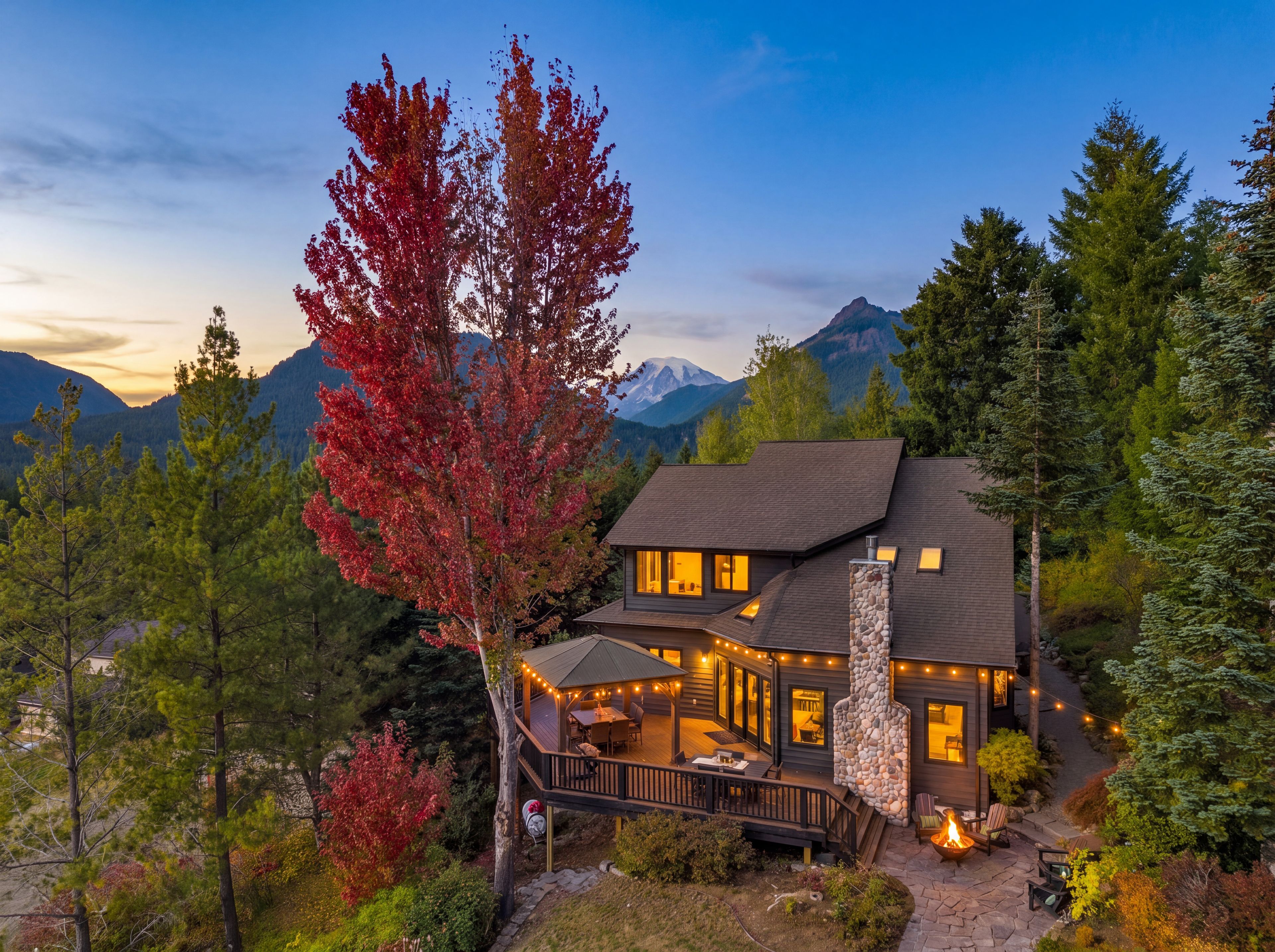 A two-story house with a deck, stone fireplace, and mountain views.