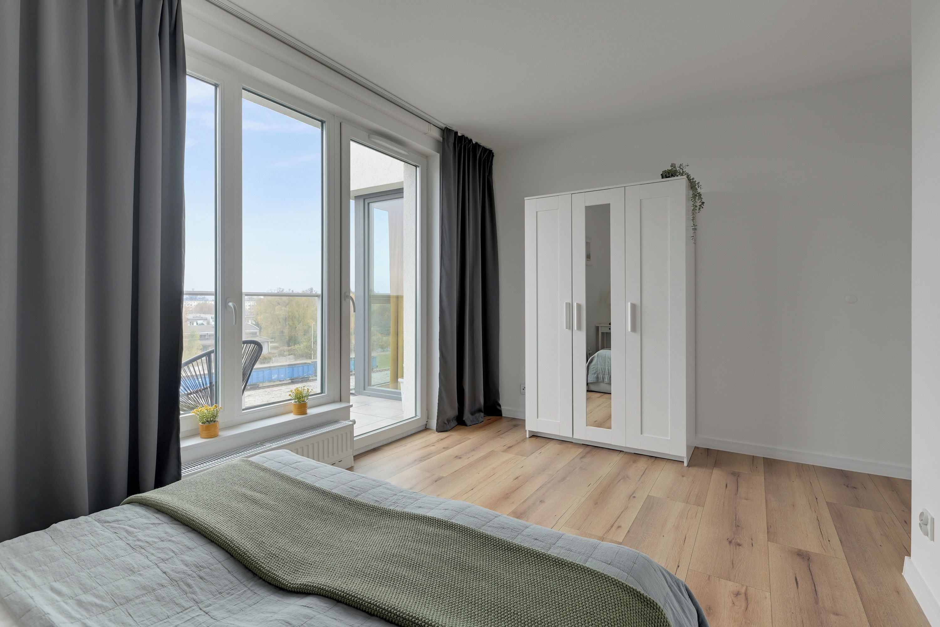Un dormitorio con un ventanal grande, una cama, un armario y vistas al exterior.