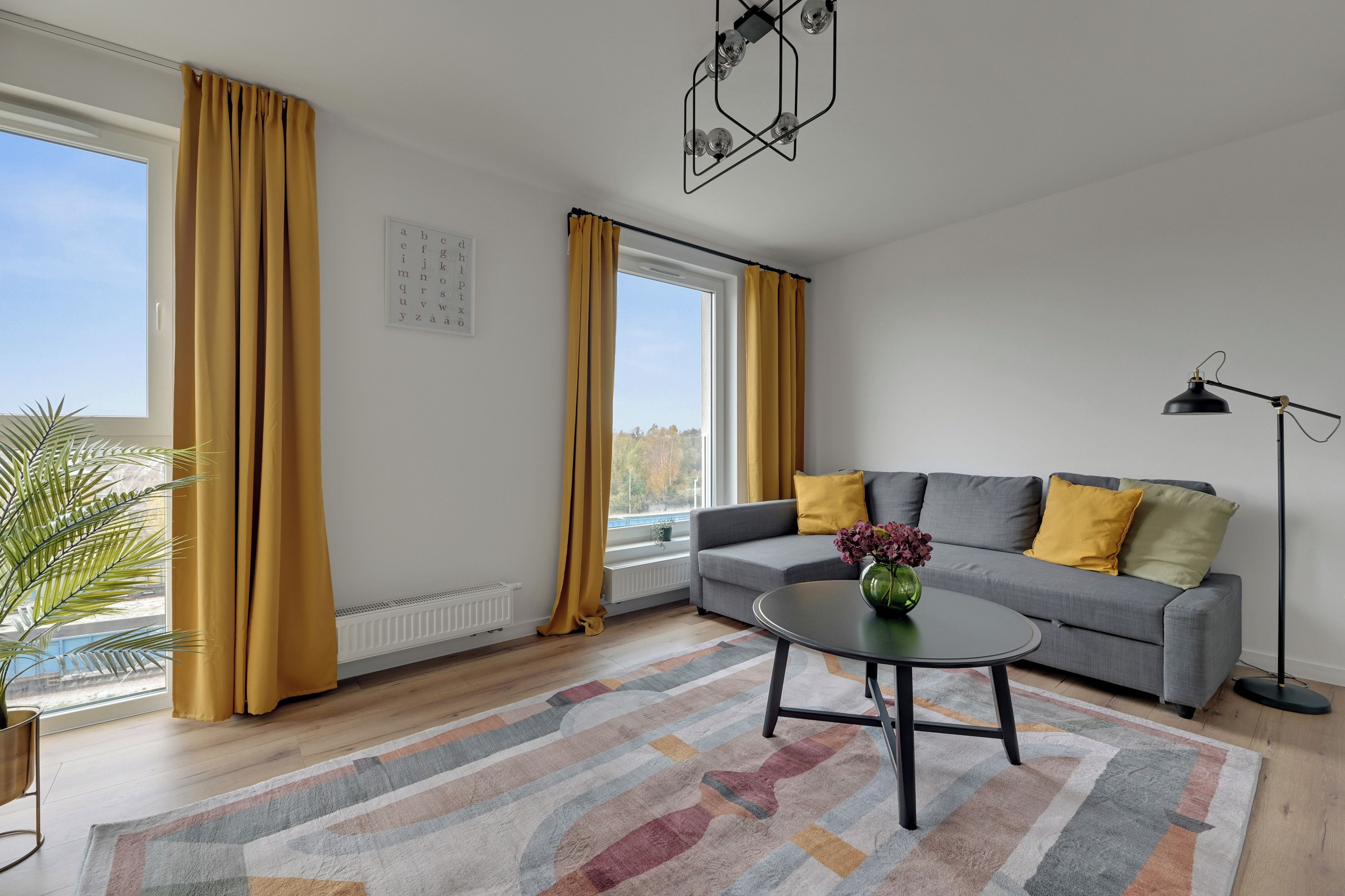 A modern living room with a grey sofa, yellow cushions, a round coffee table, and a floor lamp.