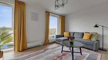 A modern living room with a grey sofa, yellow cushions, a round coffee table, and a floor lamp.