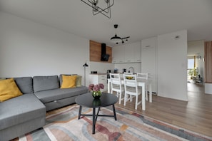 Una sala de estar moderna con un sofá seccional gris, una mesita redonda con un florero y una alfombra colorida.