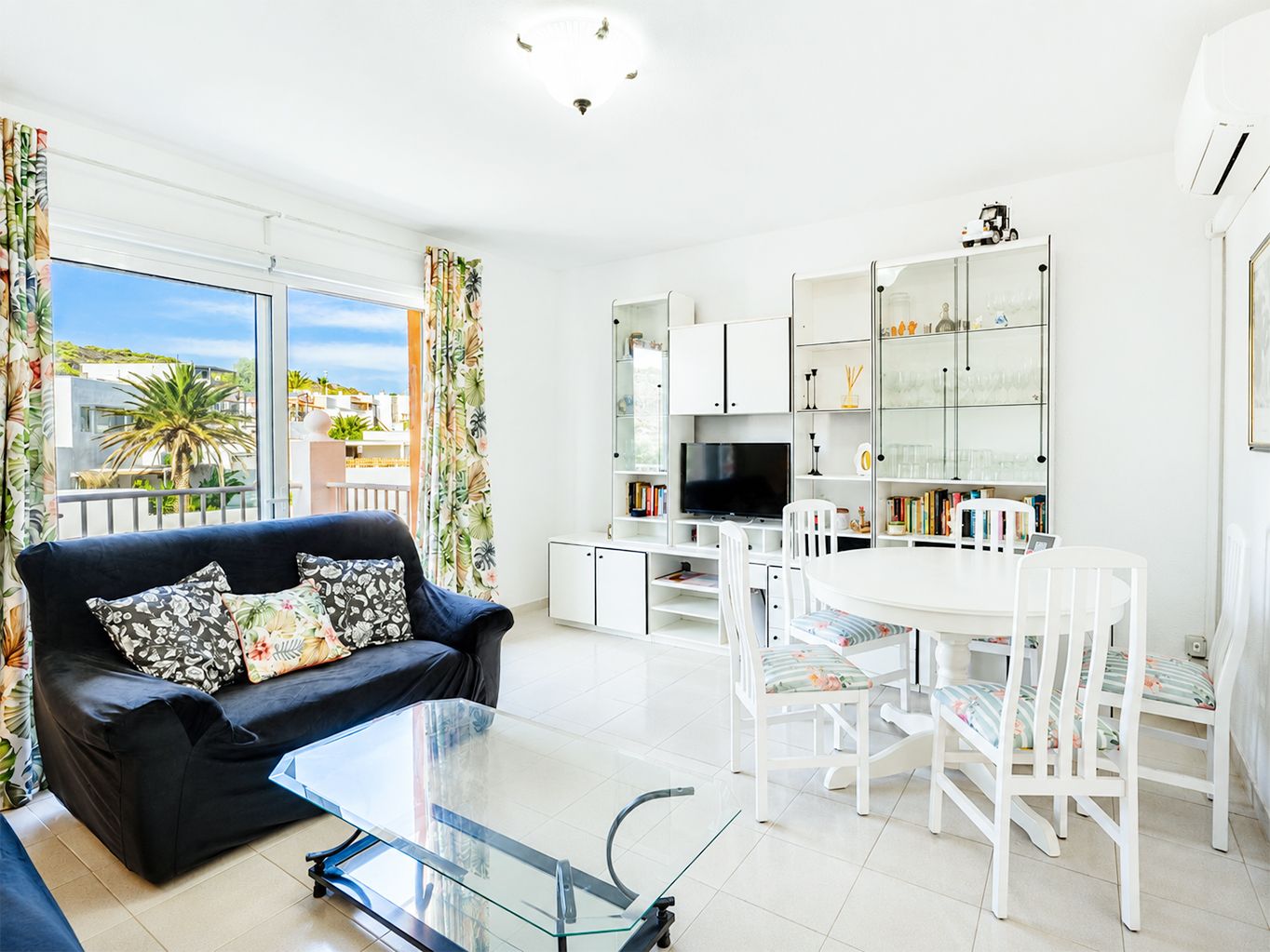 Un salon moderne avec un canapé, une table basse en verre et un coin repas comprenant des chaises et une table.