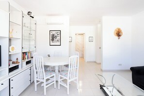 A modern, well-lit living room with a dining area, white furniture, and a minimalist decor. - Alisio Apartment in La Tejita (La Tejita)
