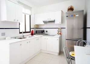 A modern kitchen with white cabinets, a stainless steel refrigerator, a microwave, and a kettle. - Alisio Apartment in La Tejita (La Tejita)