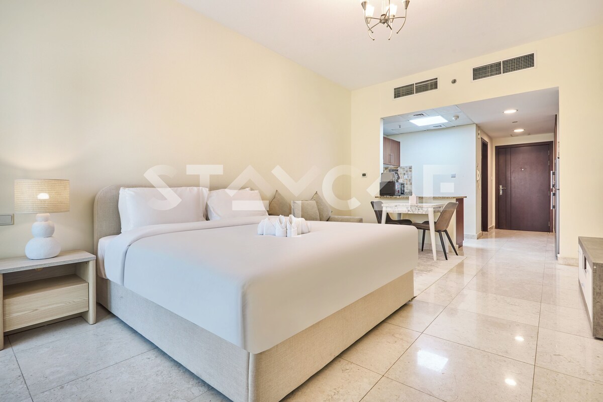 A hotel room with a large bed, a desk, and a chair.