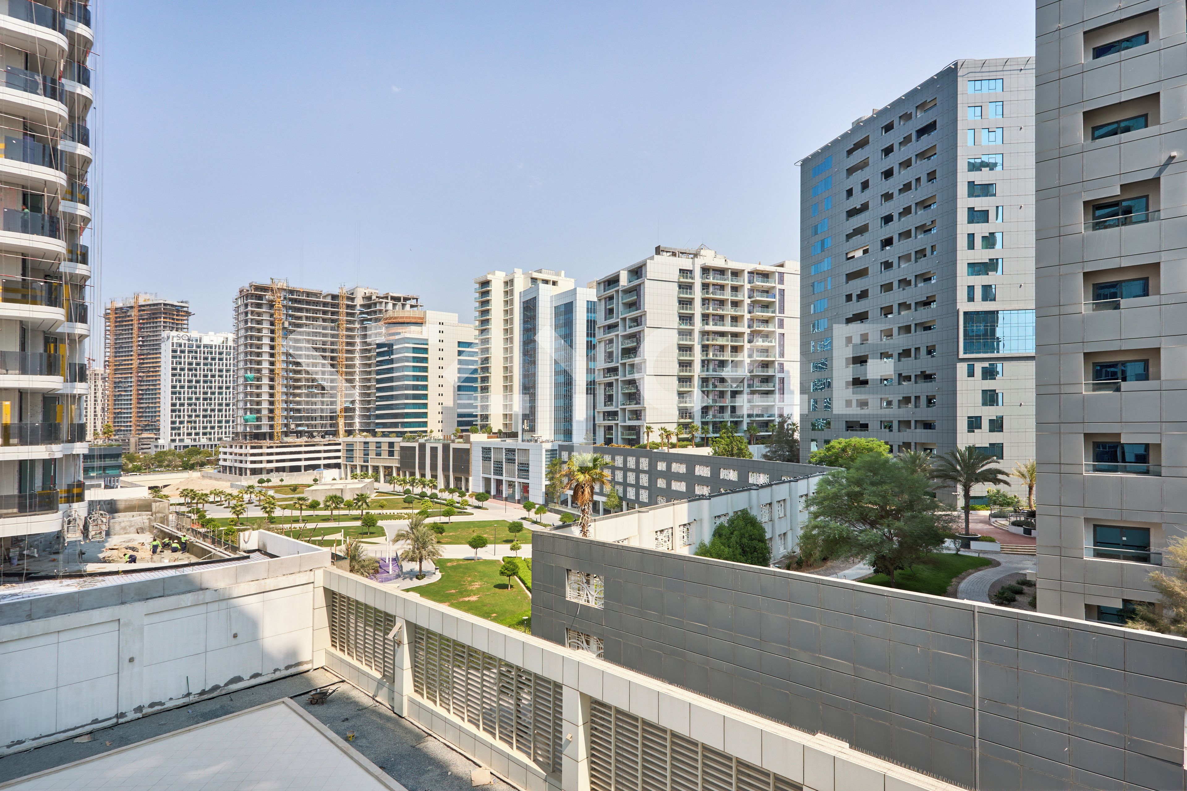 A modern high-rise building with multiple balconies and a construction site in the foreground.