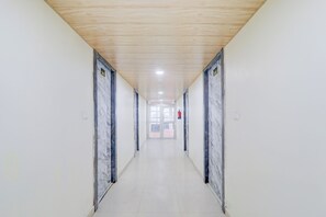 A long, narrow hallway with a wooden ceiling and marble walls, leading to a door at the end. - Collection O Ayodhya Near Airport (Faizabad)