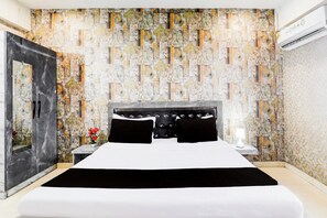 A bedroom with a bed, a nightstand, a mirror, and a wall with a patterned design. - Collection O Ayodhya Near Airport (Faizabad)
