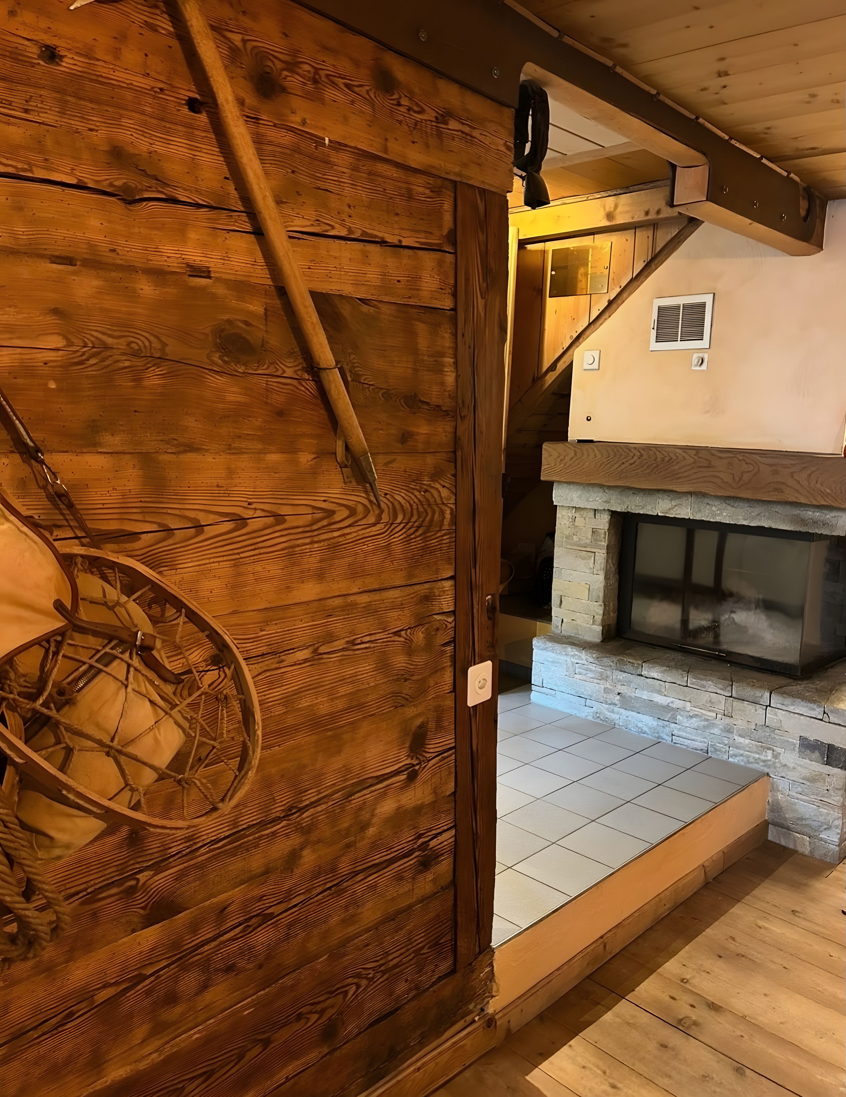 Un intérieur en bois avec une cheminée, une porte dotée d’une sonnette et un escalier.