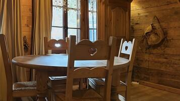 Une salle à manger en bois avec une table ronde, quatre chaises et un luminaire suspendu.