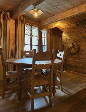 Comedor de madera con una mesa redonda, cuatro sillas y una lámpara colgante.