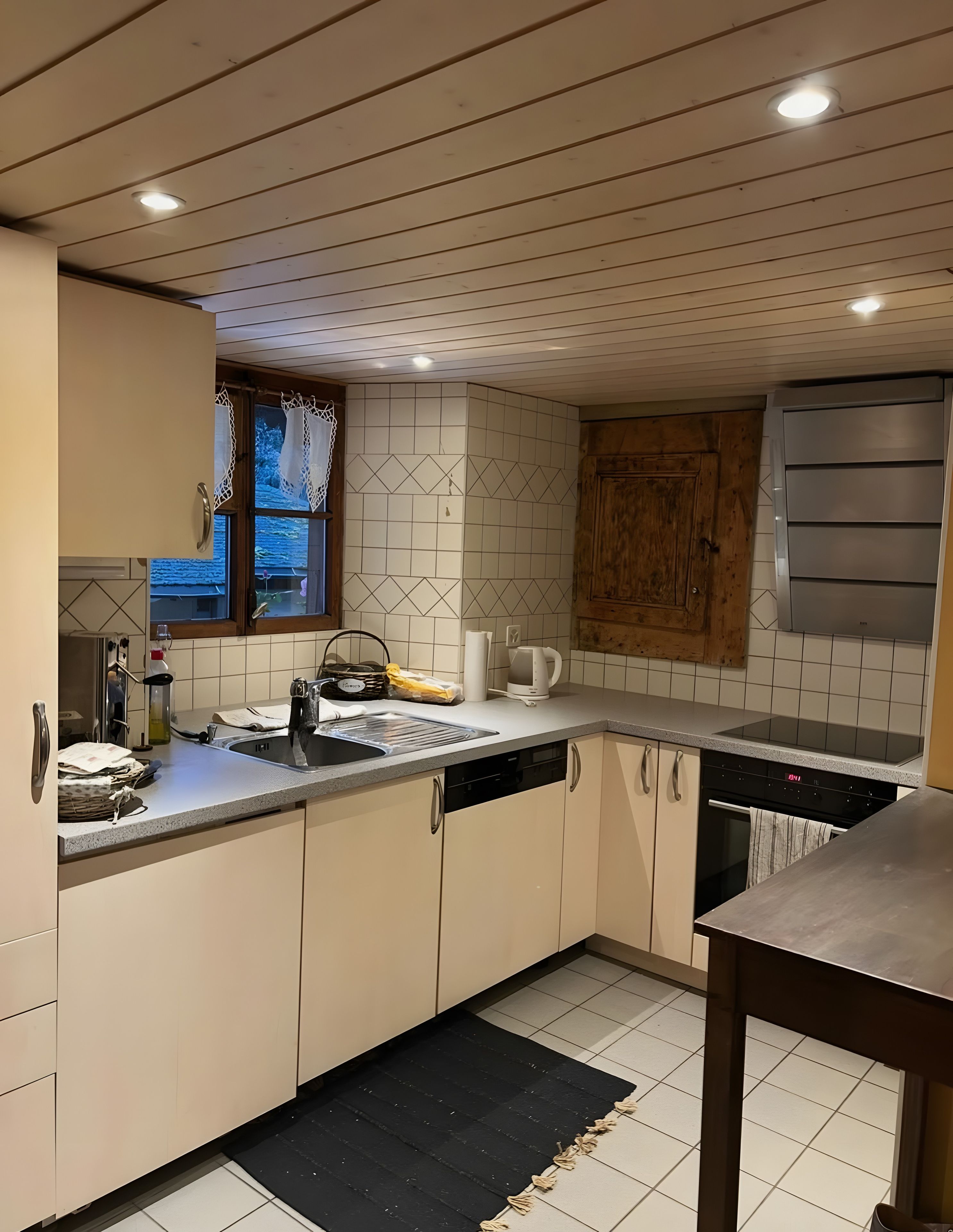 Une cuisine équipée d’un lave-vaisselle, d’une cuisinière et d’une fenêtre avec des rideaux.