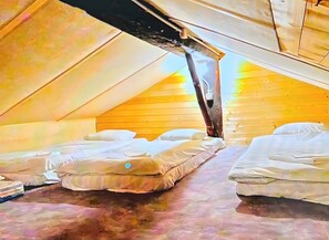 Ein Zimmer mit zwei Betten, Holzwänden und einer schrägen Decke.