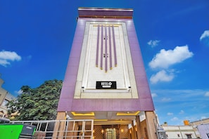 Un hotel amb un cartell vertical destacat, façana amb un disseny decoratiu i cel blau al fons.
