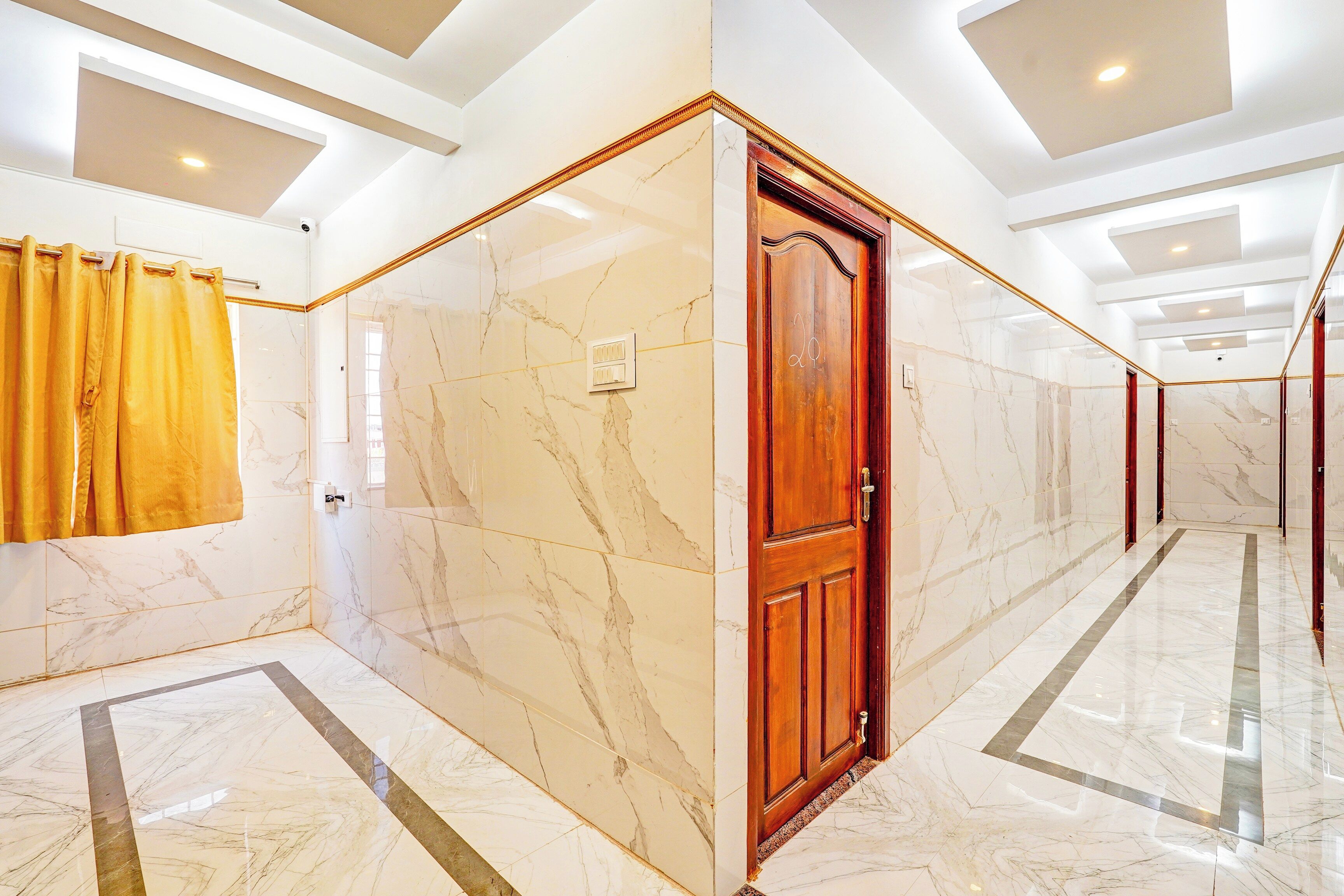 A corridor with marble flooring, a wooden door, and a yellow curtain.